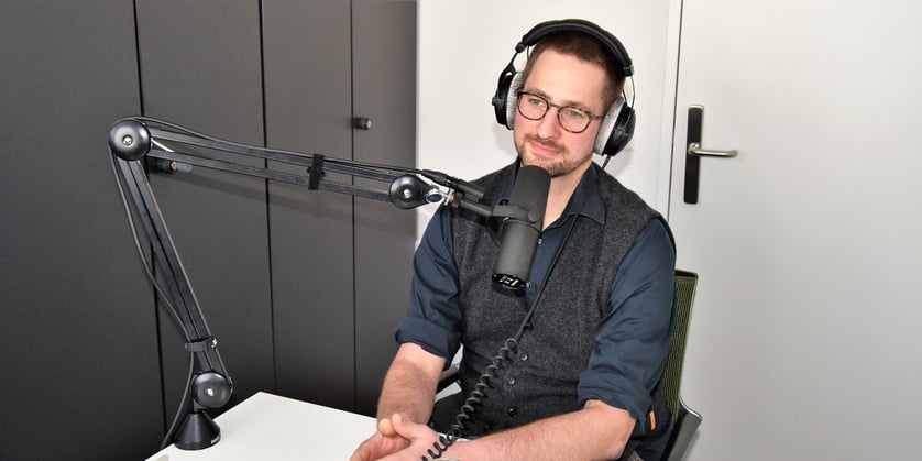 Michael Glas, Leitender Arzt Intensivmedizin Spital Emmental, mit Mikrofon bei Podcast-Aufnahme.