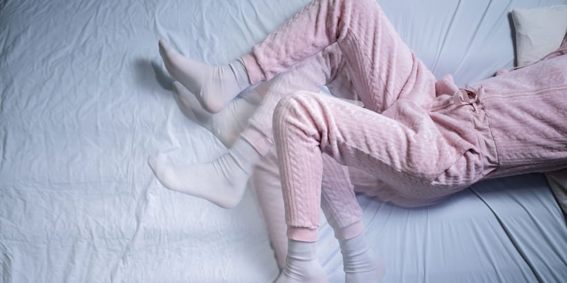 Restless Legs: Eine Frau im rosa Pijama zappelt mit den Beinen. 